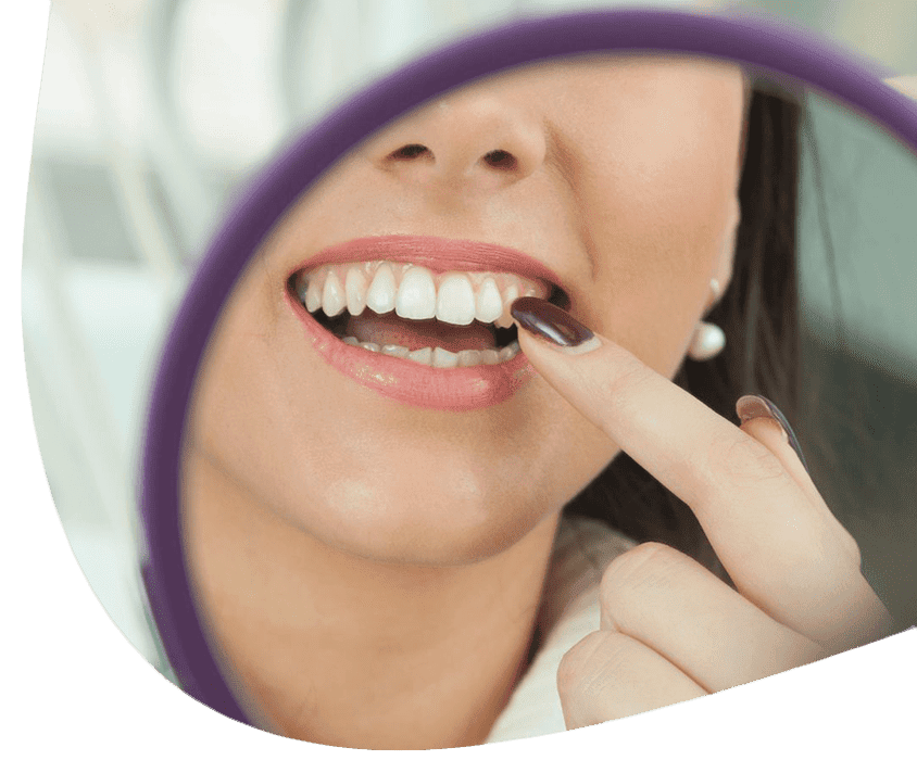 Žena s bielym úsmevom ukazuje na svoj zub.